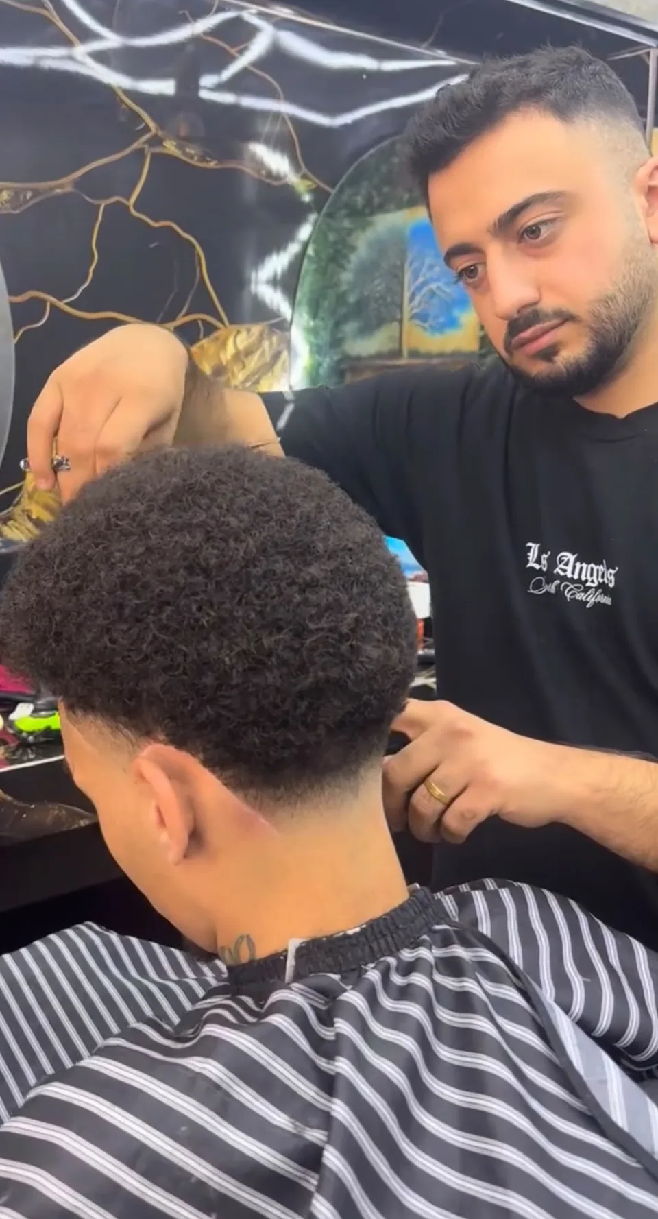 Barber arbeitet die Seiten eines lockigen Haarschnitts mit der Schere aus